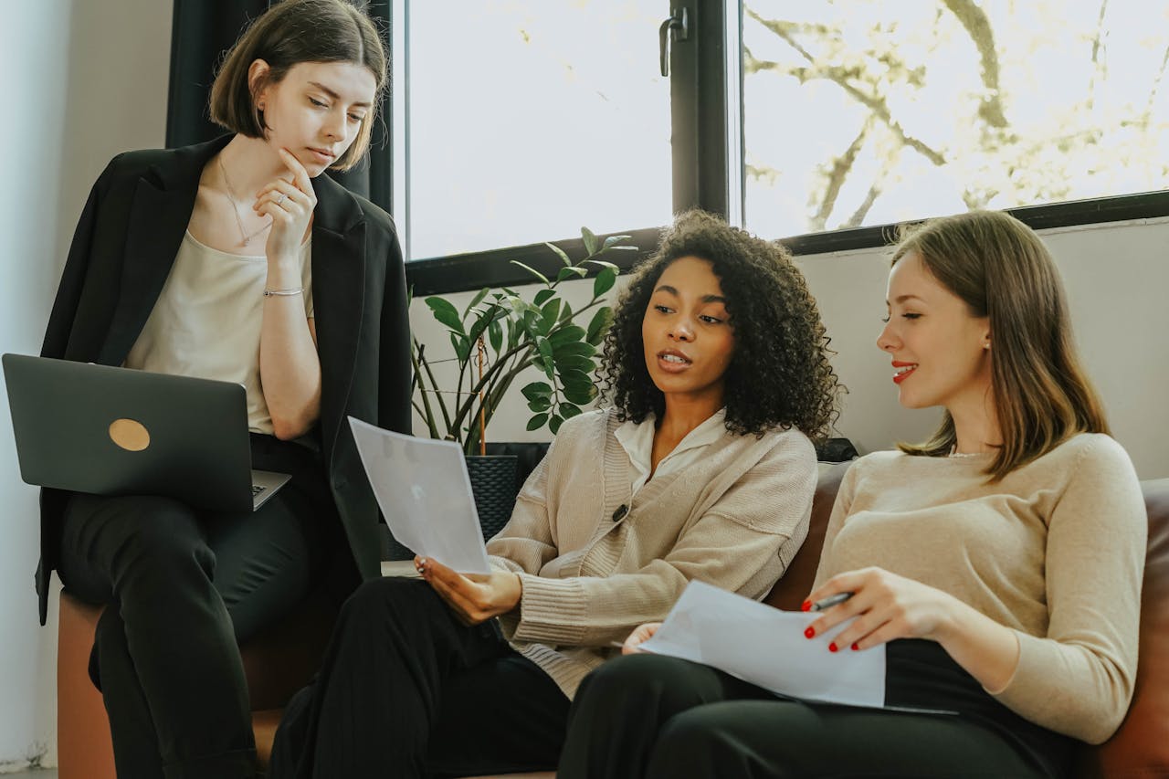 Three professional women engaged in a collaborative meeting in a modern office setting.